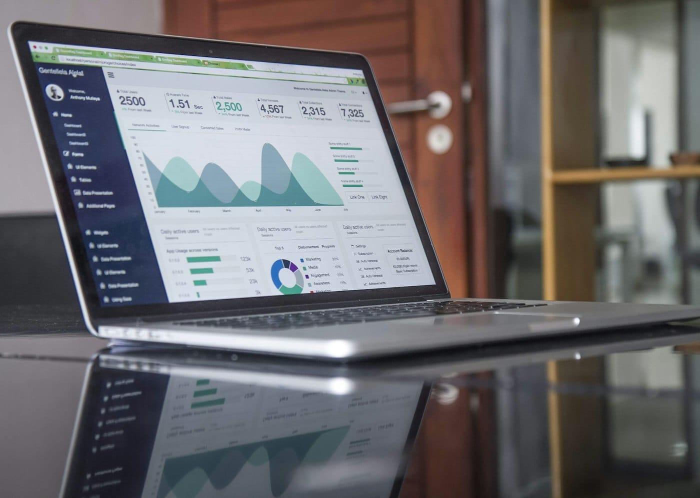 Laptop displaying analytics charts beside a notebook